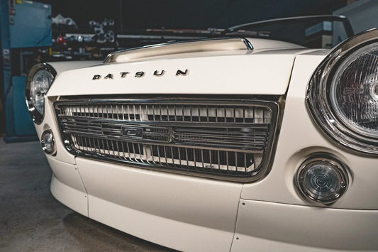 Side angle view of a classic white Datsun 2000 roadster.