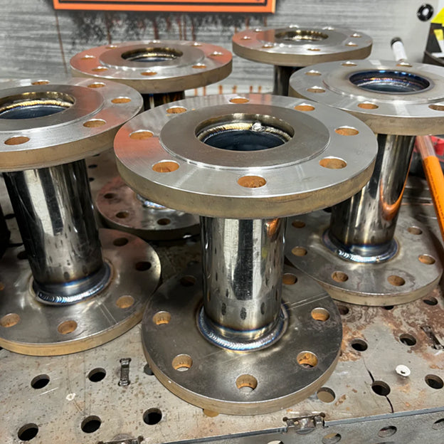 Collection of metal flanges on a workshop table.